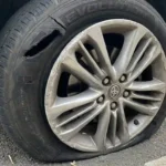 Severe tyre sidewall blowout puncture and damaged alloy wheel rim on roadside in London