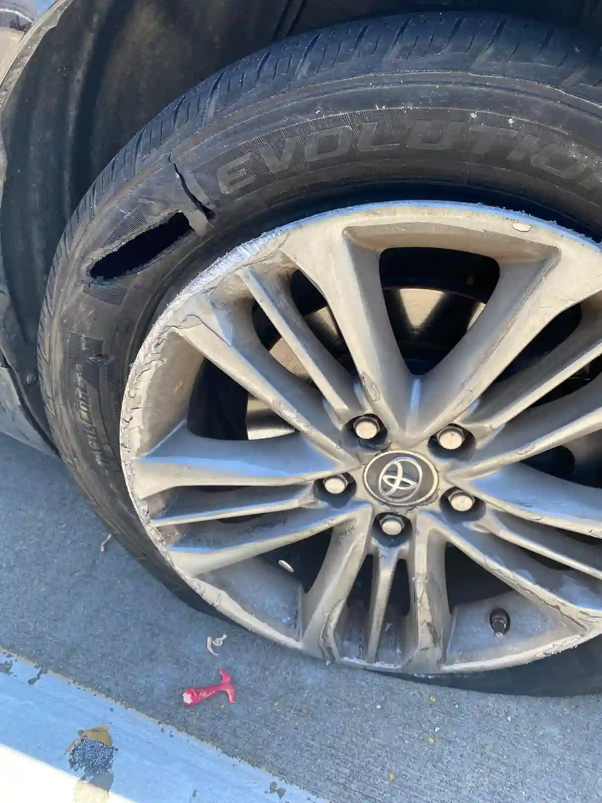 Mobile tyre technician inspecting a damaged car tyre after a tyre emergency